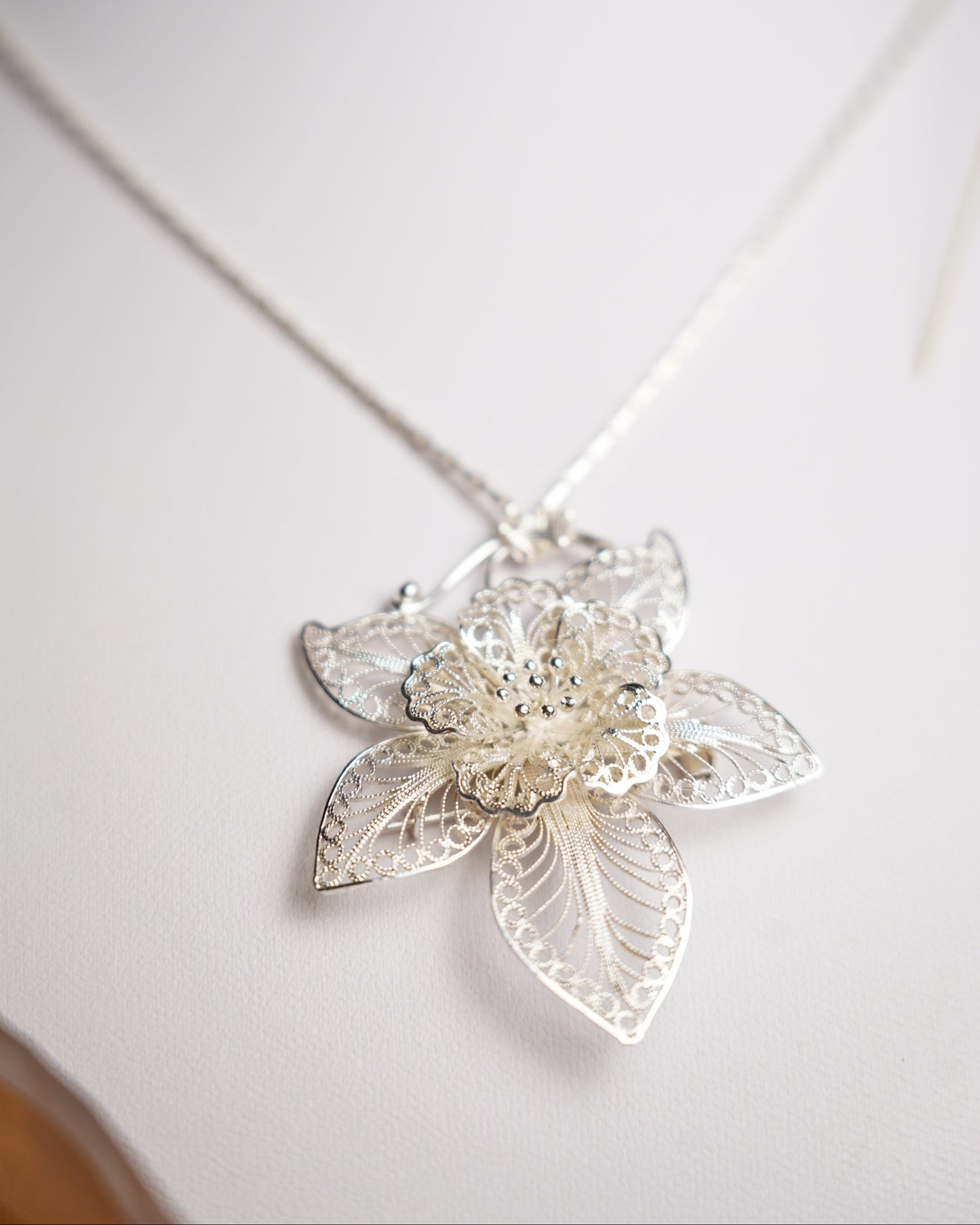 Halskette aus 925/- Sterlingsilber mit filigran gearbeitetem Blütenanhänger und floralen Verzierungen.