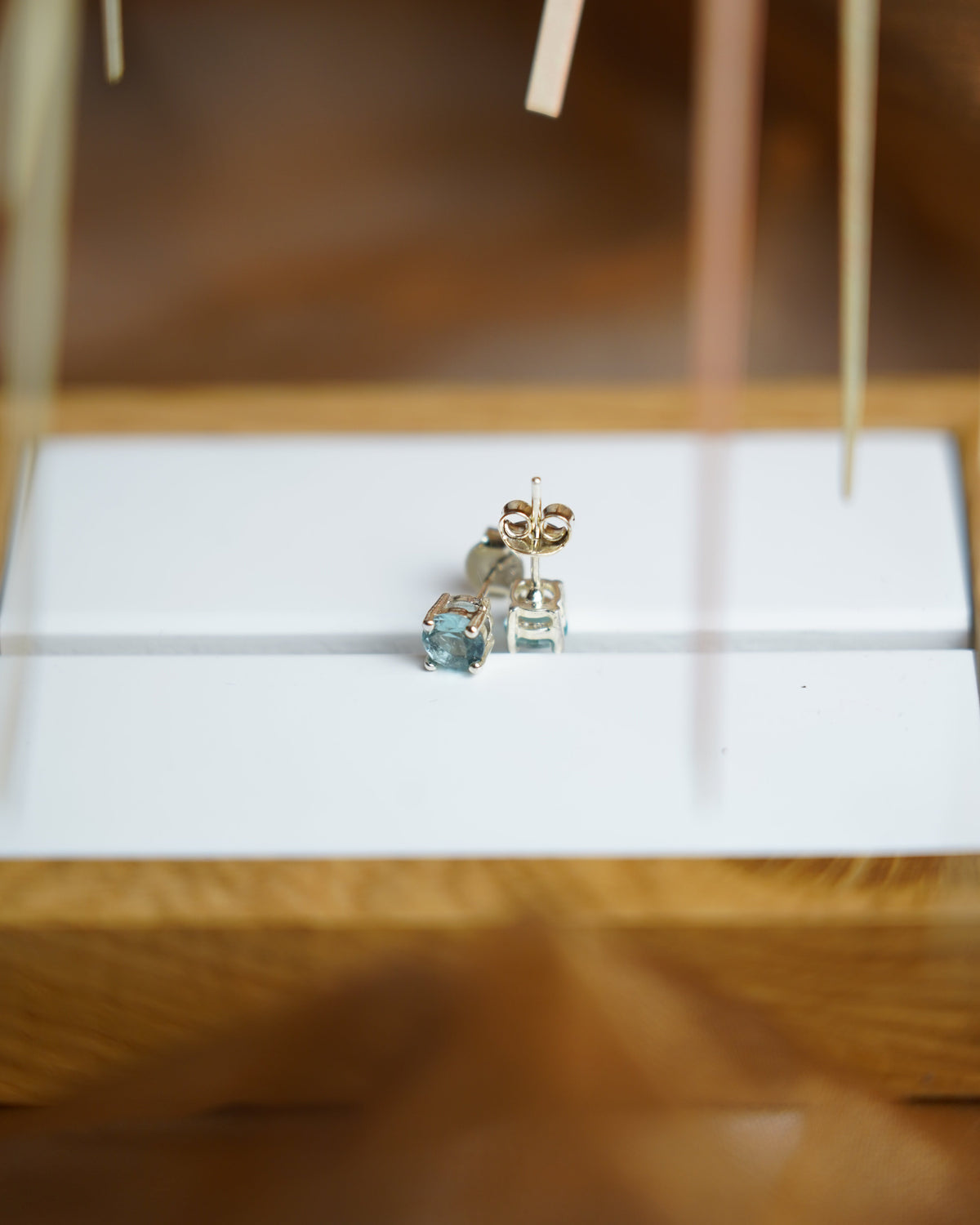 Blue Glow Ohrstecker aus 925/- Sterlingsilber mit blau gefärbten Zirkoniasteinen, Vier-Krappen-Fassung und Steckverschluss auf weißer Schmuckunterlage.