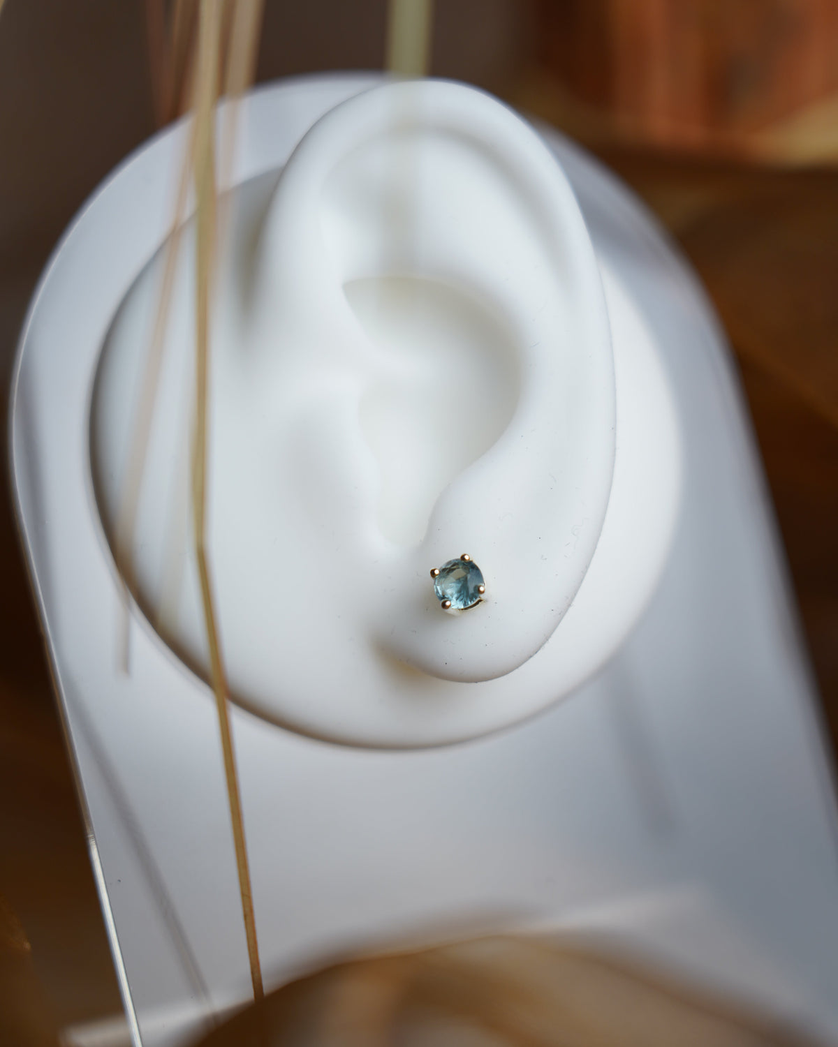 Blue Glow Ohrstecker aus 925/- Sterlingsilber mit hellblauem, facettiertem Zirkoniastein in Vier-Krappen-Fassung auf weißem Ohrdisplay.