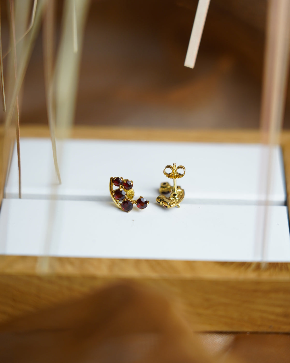 Crimson Vine Ohrstecker aus 333/- Gelbgold mit mehreren facettierten roten Granatsteinen in geschwungener Anordnung.
