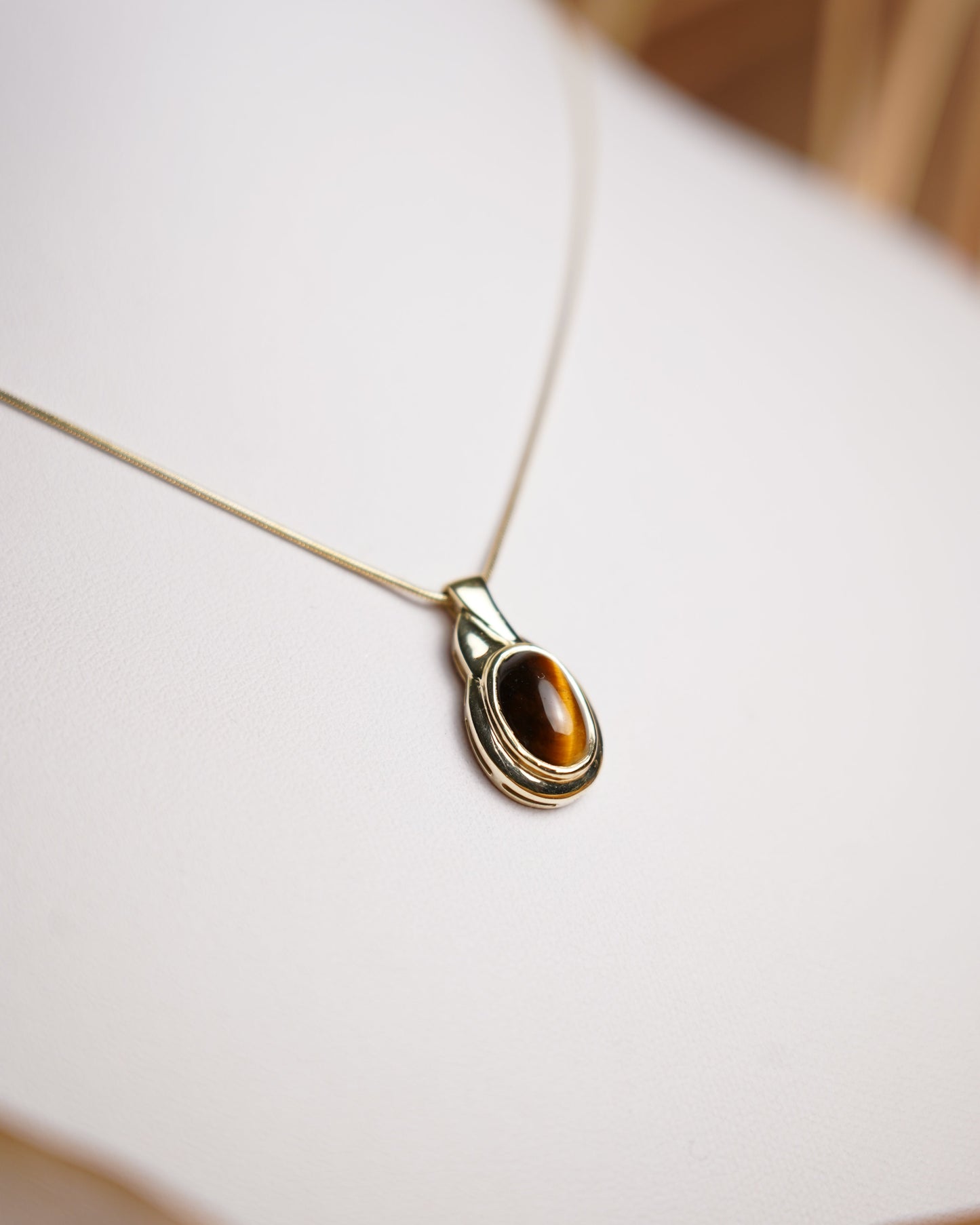 Halskette aus 585 Gelbgold mit ovalem Tigerauge-Anhänger in eleganter, zeitloser Fassung.