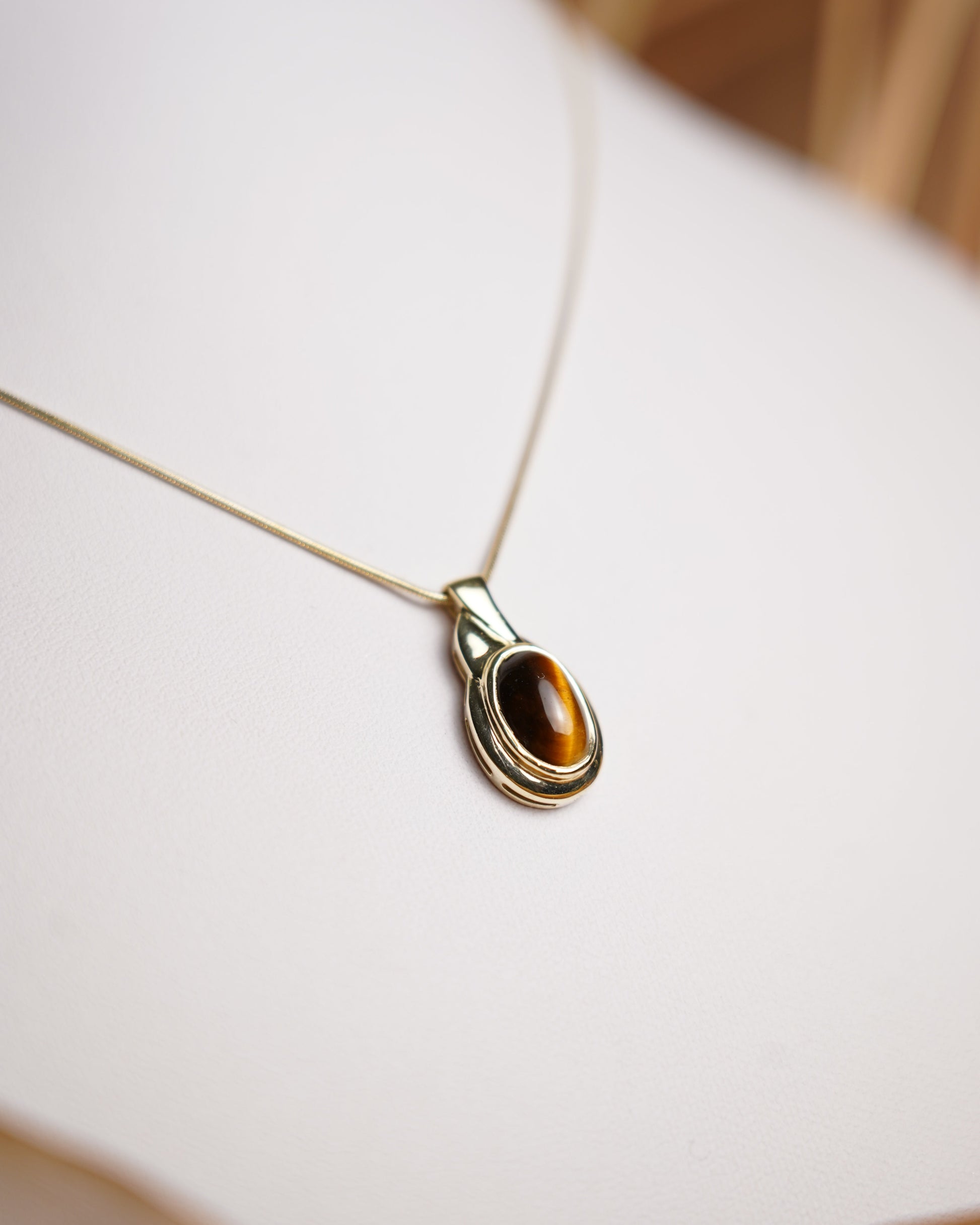 Halskette aus 585 Gelbgold mit ovalem Tigerauge-Anhänger in eleganter, zeitloser Fassung.