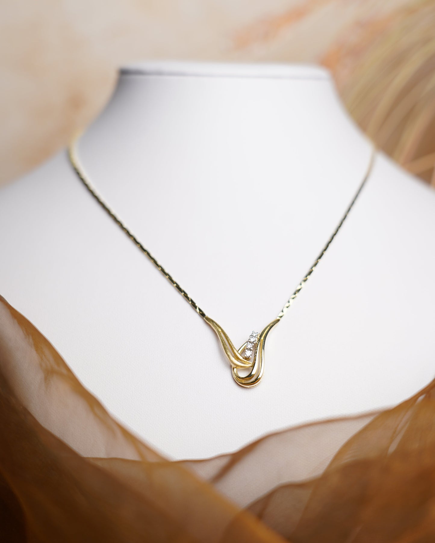 Halskette Golden Harmony aus 585/- Gelbgold mit geschwungenem Anhänger und funkelnden Brillianten auf weißem Schmuckdisplay.