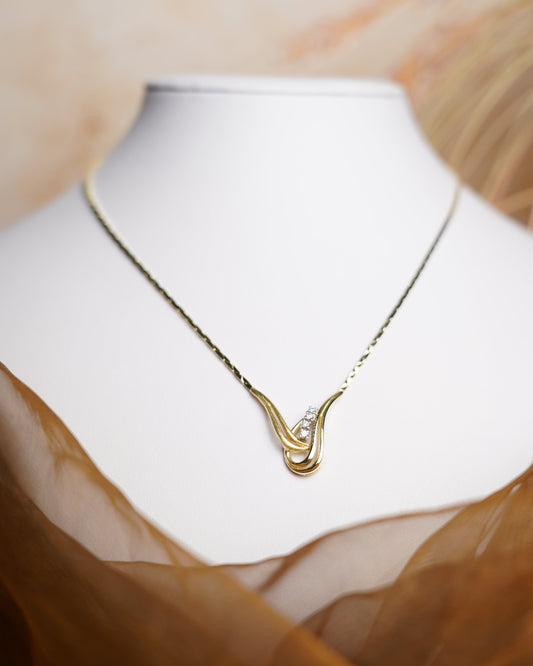 Halskette Golden Harmony aus 585/- Gelbgold mit geschwungenem Anhänger und funkelnden Brillianten auf weißem Schmuckdisplay.