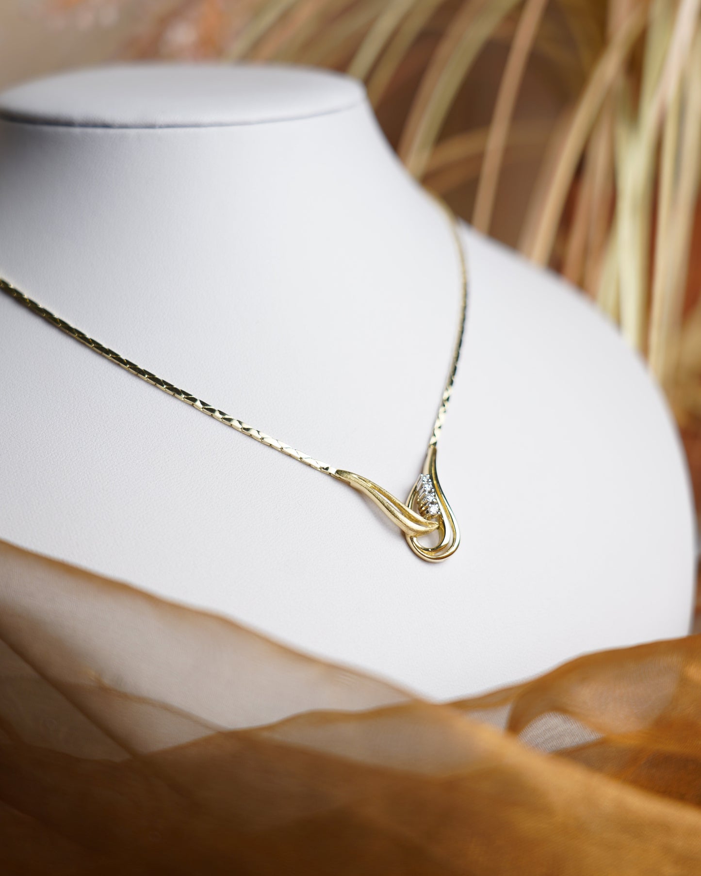Halskette Golden Harmony aus 585/- Gelbgold mit geschwungenem Anhänger und funkelnden Brillianten auf weißem Schmuckdisplay.