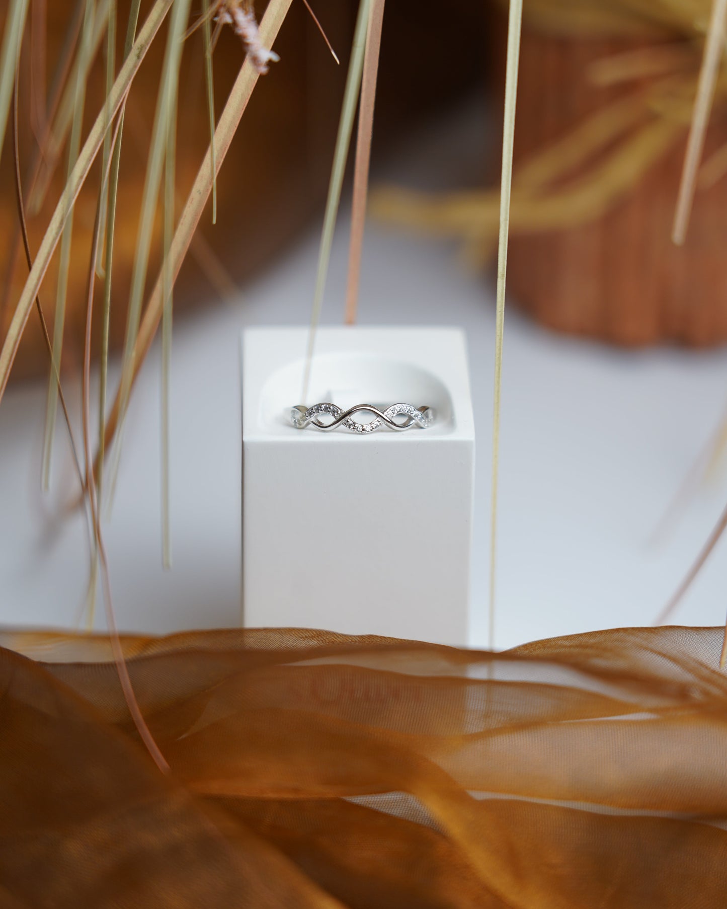 Ring Infinity Spark aus 925/- Sterlingsilber mit geschwungenem Unendlichkeitsdesign und funkelnden Zirkoniasteinen auf weißem Präsentationsständer.