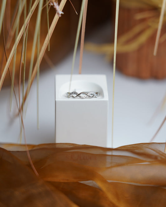 Ring Infinity Spark aus 925/- Sterlingsilber mit geschwungenem Unendlichkeitsdesign und funkelnden Zirkoniasteinen auf weißem Präsentationsständer.