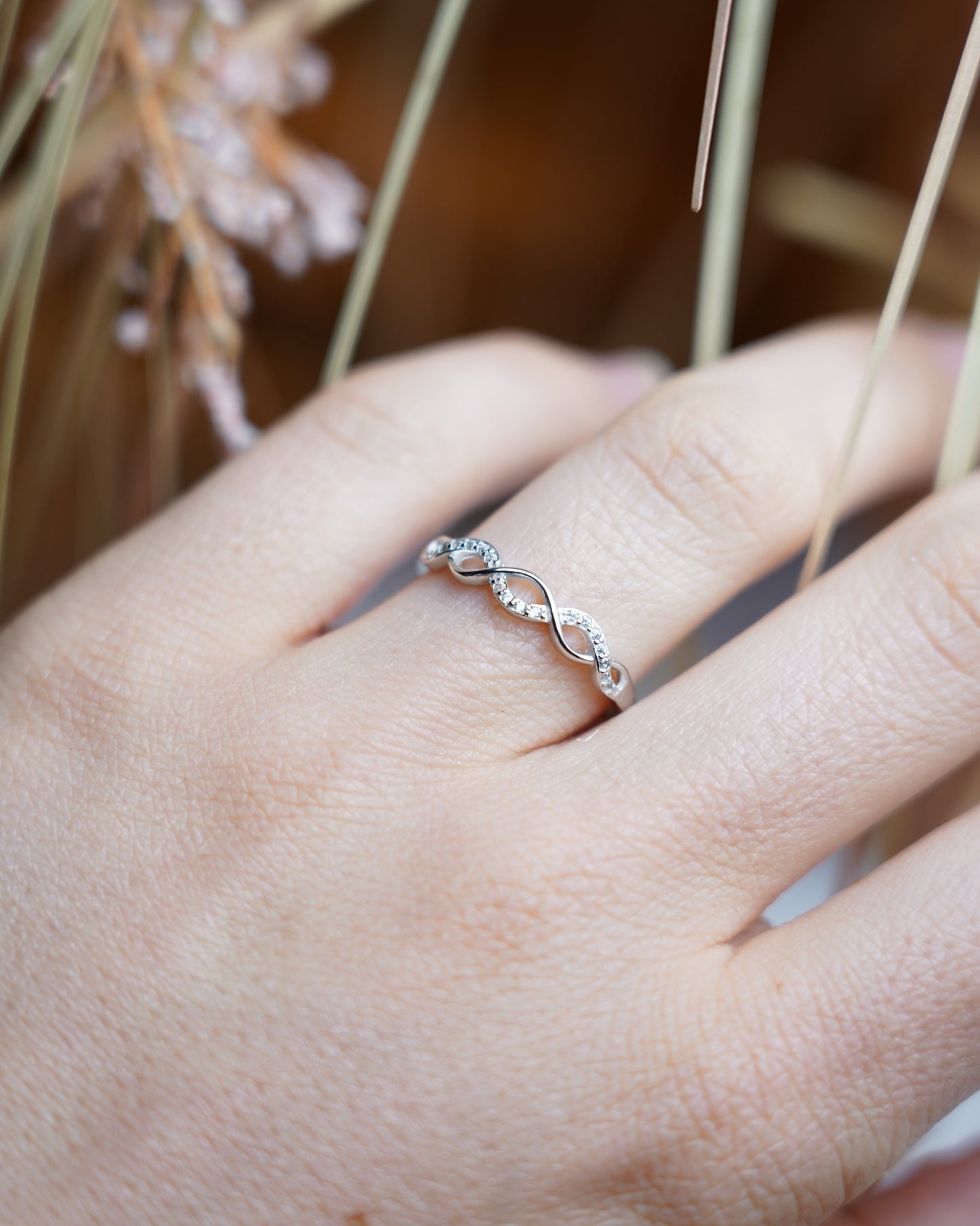 Ring Infinity Spark aus 925/- Sterlingsilber mit geschwungenem Unendlichkeitsdesign und funkelnden Zirkoniasteinen auf weißem Präsentationsständer.