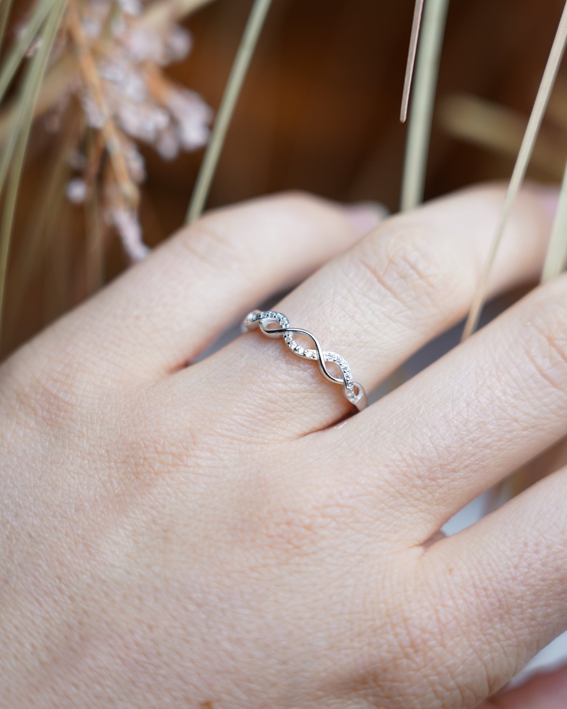 Ring Infinity Spark aus 925/- Sterlingsilber mit geschwungenem Unendlichkeitsdesign und funkelnden Zirkoniasteinen auf weißem Präsentationsständer.