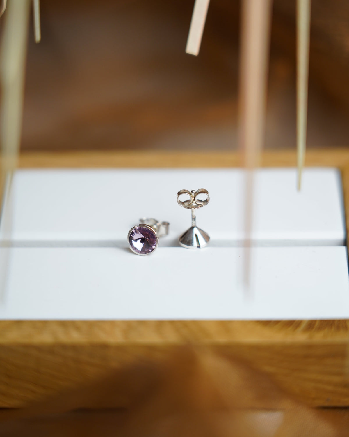 Lilac Spark Ohrstecker aus 925/- Sterlingsilber mit runden, facettierten Glassteinen in zartem Lila, auf weißem Schmuckdisplay präsentiert.