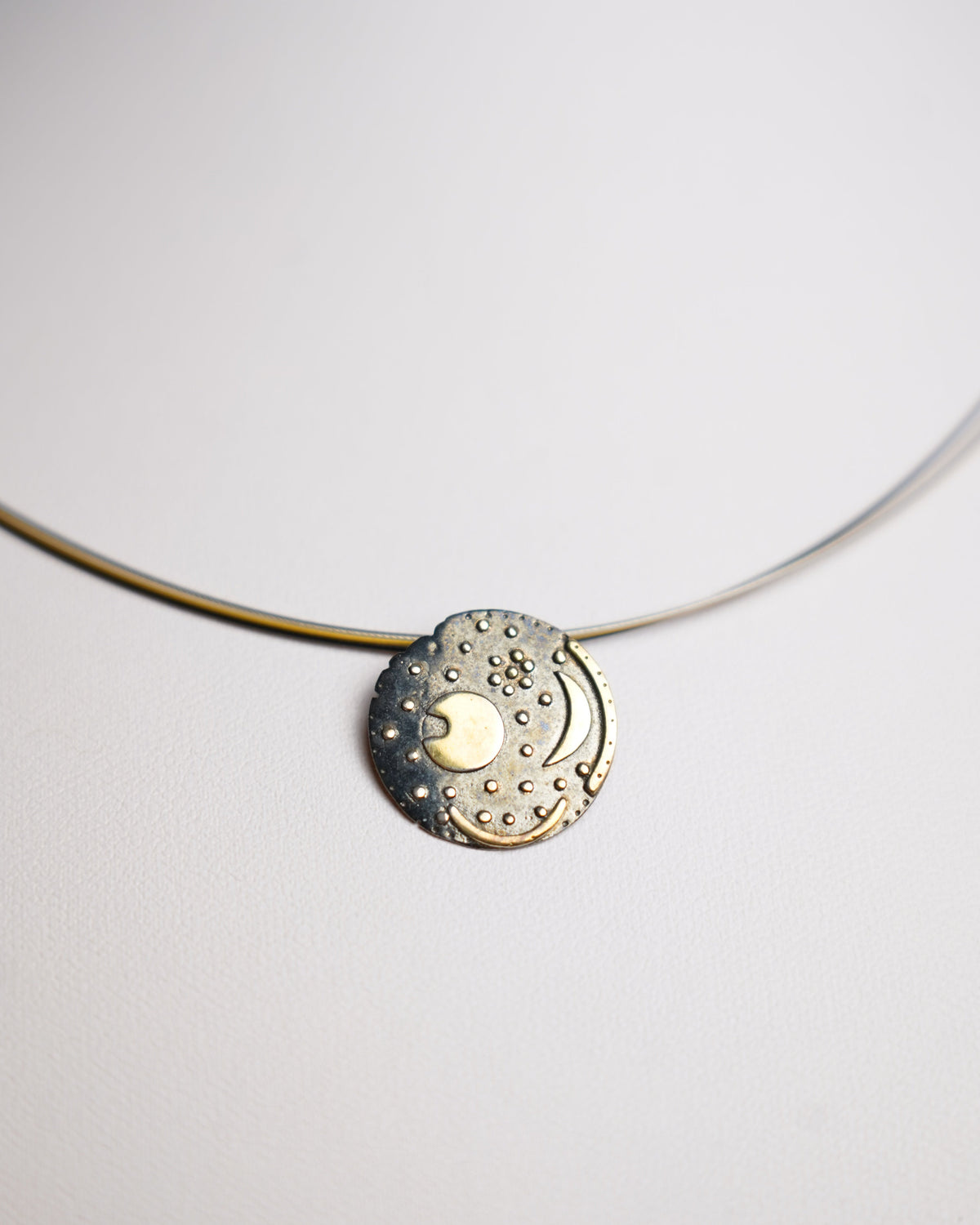 Nebra Sky Halskette aus 925/- Sterlingsilber mit rundem Anhänger nach dem Motiv der Himmelsscheibe von Nebra, geschwärzt und teilvergoldet.