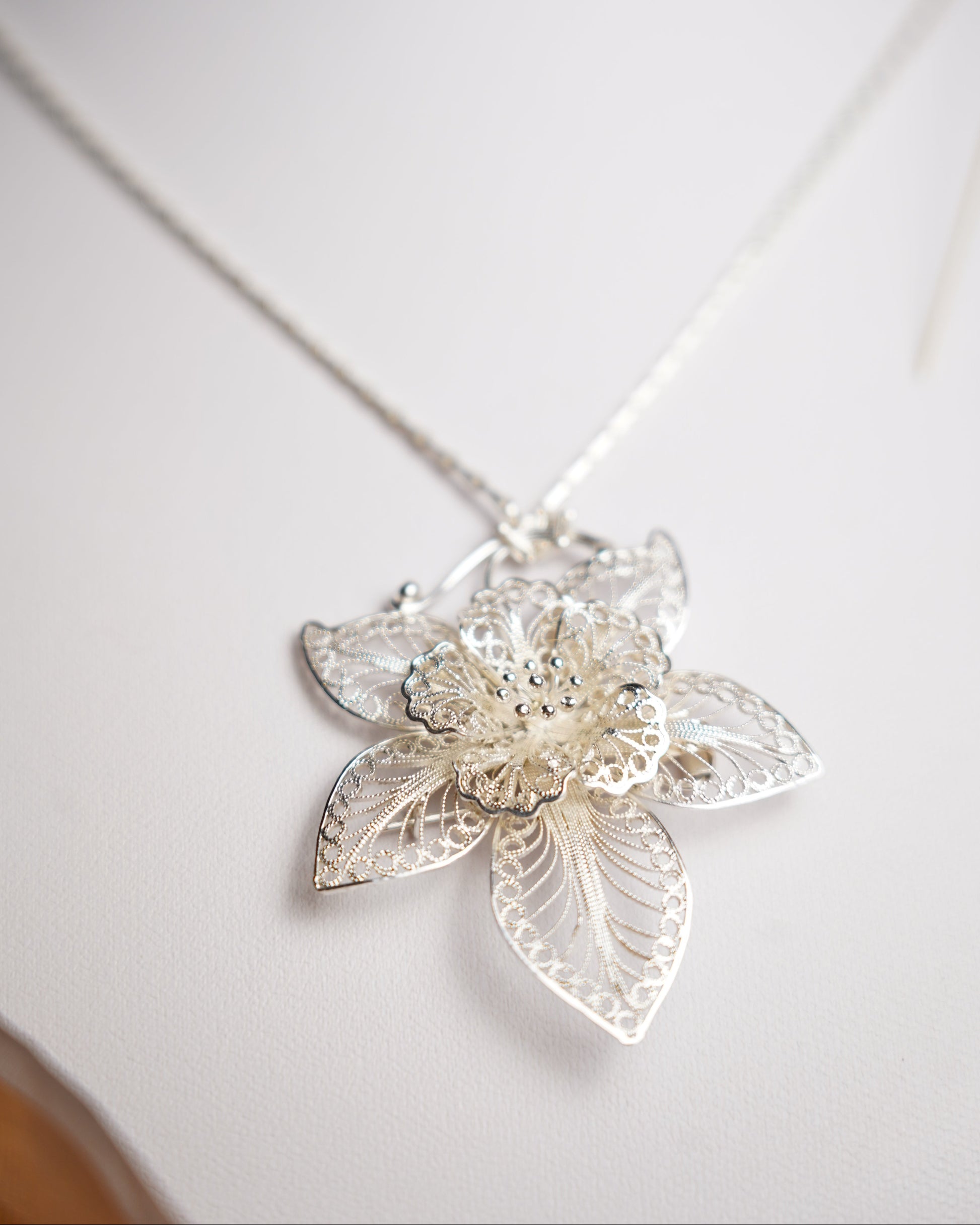 Halskette aus 925/- Sterlingsilber mit filigran gearbeitetem Blütenanhänger und floralen Verzierungen.