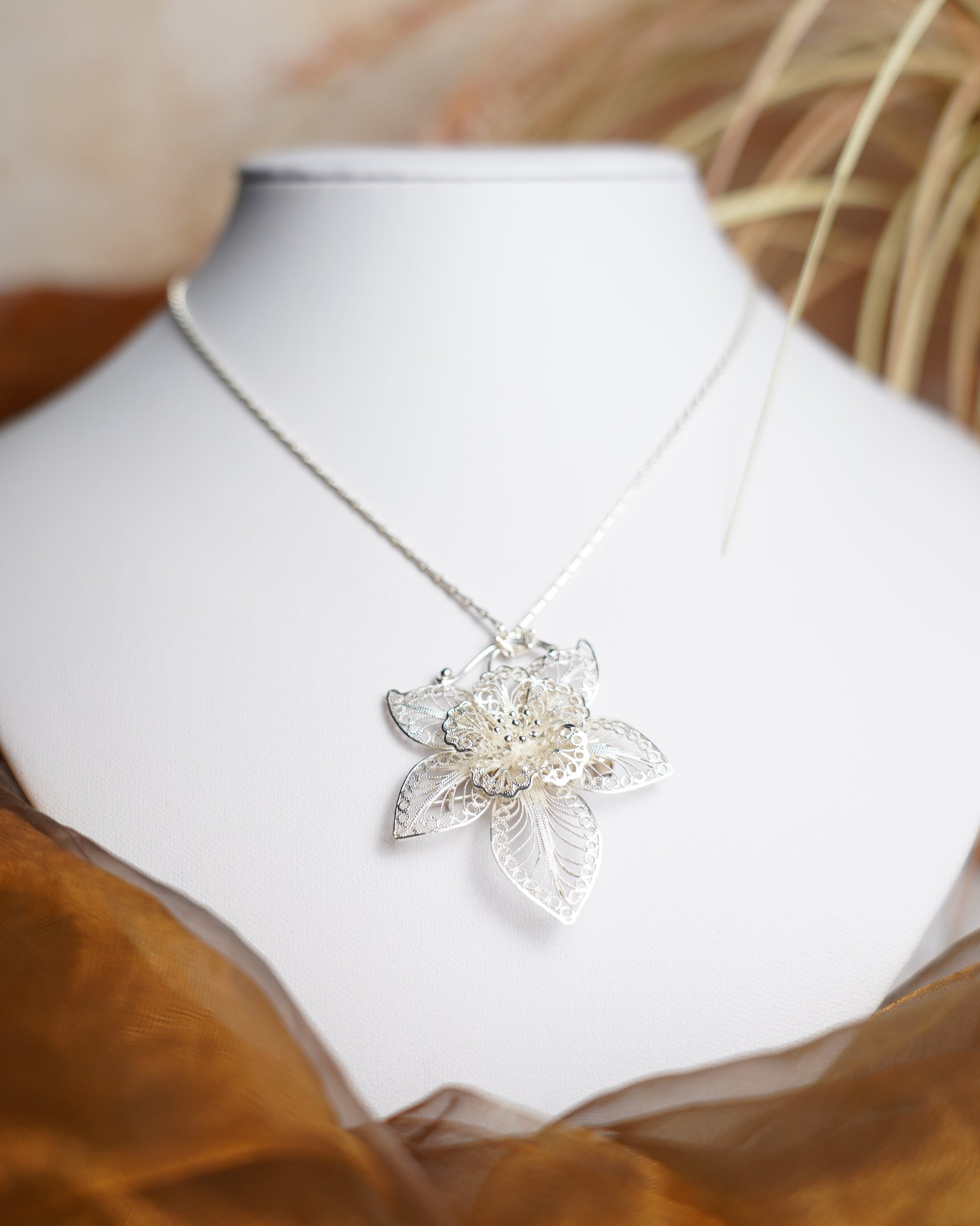 Halskette aus 925/- Sterlingsilber mit filigran gearbeitetem Blütenanhänger und floralen Verzierungen.