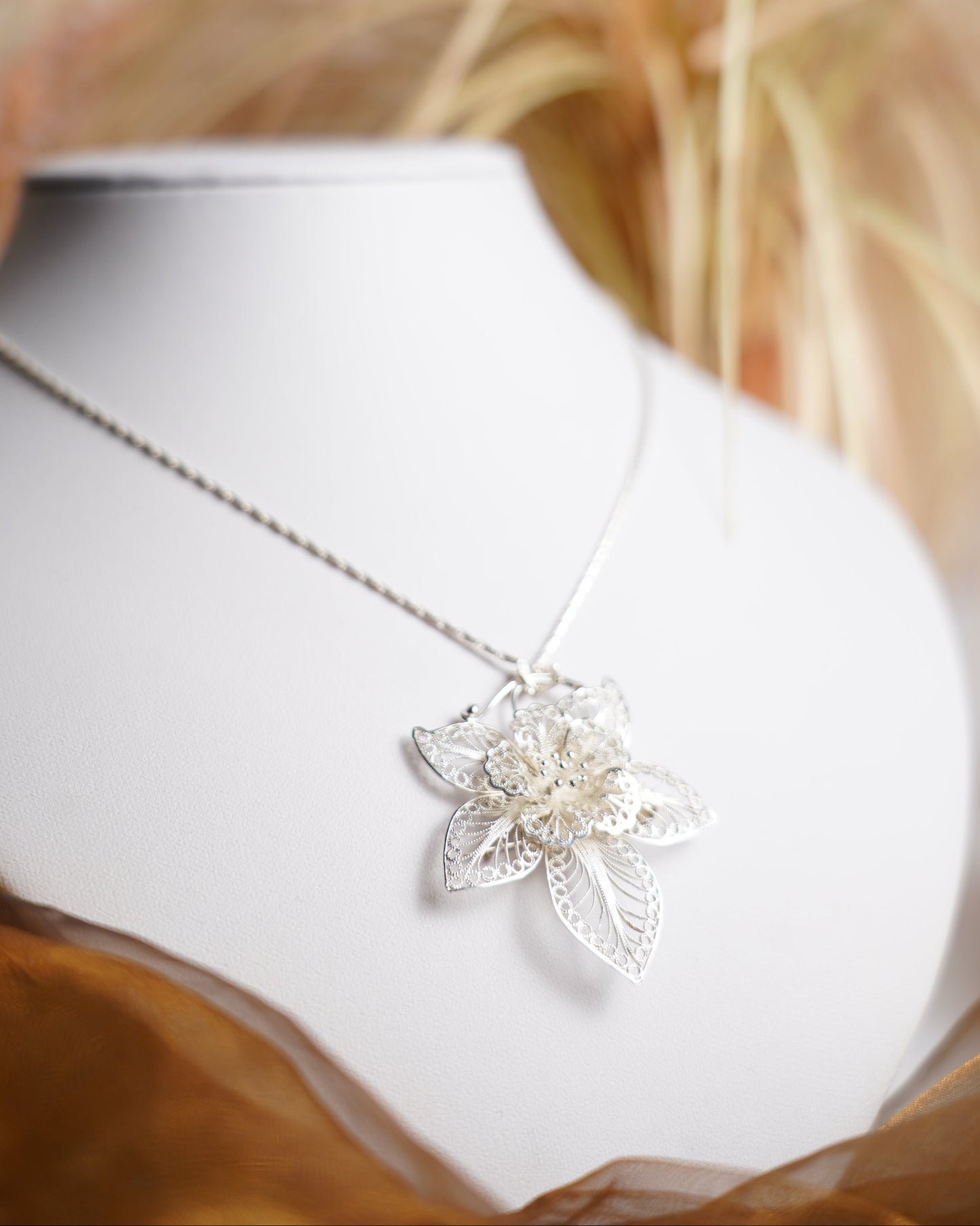 Halskette aus 925/- Sterlingsilber mit filigran gearbeitetem Blütenanhänger und floralen Verzierungen.